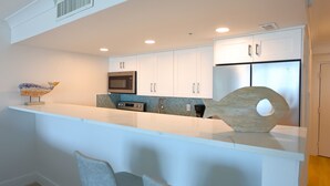 A modern kitchen with white cabinets, a built-in microwave, and a stainless steel refrigerator. - Casa Playa #502 Beach Front - Gulf Front Getaway (Fort Myers Beach)
