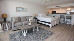 A modern, minimalist bedroom with a bed, a sofa, a coffee table, and a small kitchen area. - Casa Playa #502 Beach Front - Gulf Front Getaway (Fort Myers Beach)