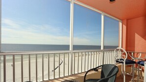 Un balcon avec vue sur la plage, une table ronde et deux chaises.
