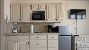 A kitchen with beige cabinets, a microwave, a coffee maker, and a refrigerator.