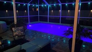 A covered outdoor swimming pool with blue lighting, surrounded by seating and potted plants. - Near beach• Hot tub• Heated pool• Fenced yard •Carport• Pet friendly•Private (Venice)