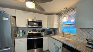 A modern kitchen with stainless steel appliances, white cabinetry, and a patterned backsplash. - Near beach• Hot tub• Heated pool• Fenced yard •Carport• Pet friendly•Private (Venice)