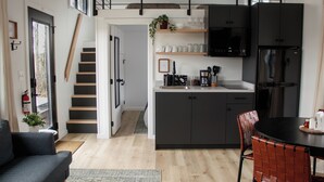 A modern kitchen with dark cabinets, a black refrigerator, and a dining area with a round table and red chairs.
