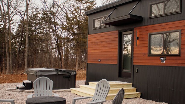 A modern outdoor seating area with Adirondack chairs and a fire pit, surrounded by a gravel patio.