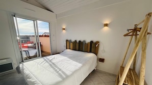 A bedroom with a bed, a wooden headboard, a wooden ladder, and a sliding glass door leading to an outdoor area.