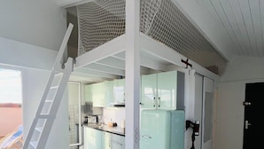 A modern kitchen with a built-in refrigerator, a ladder leading to an upper level, and a view of the outside.
