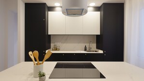 Eine moderne Küche mit Schwarz-Weiß-Farbgebung, ausgestattet mit einem eingebauten Herd, einer Spüle und einer Arbeitsplatte mit Pflanze und Holzkochlöffeln.