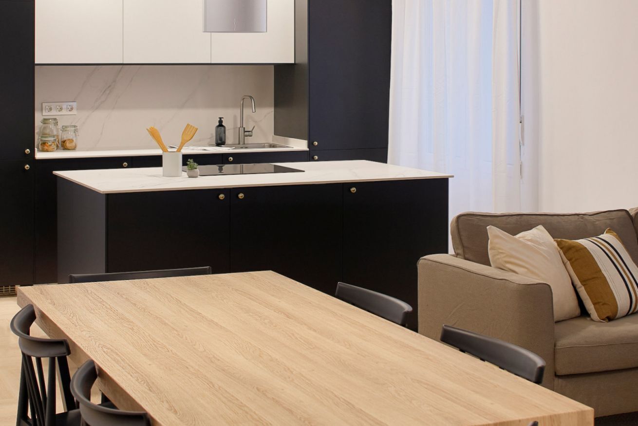 Cozinha compacta com ilha central, mesa de jantar e sofá.