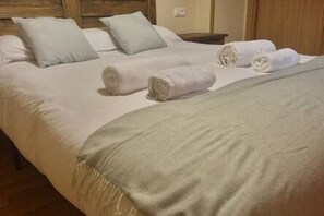 Una cama bien hecha con almohadas y toallas enrolladas.