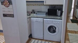 Una cocina compacta con lavadora, microondas y una pequeña encimera.