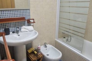 Un baño con lavamanos, espejo y bidé.