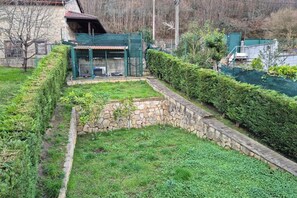 Un muro de piedra, una siega verde y un área cercada con techo.