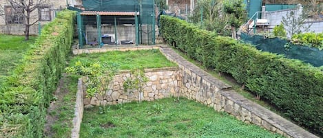 Un muro de piedra, una siega verde y un área cercada con techo.