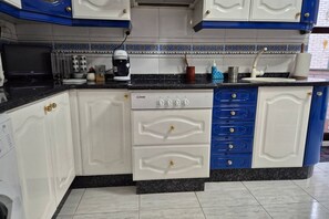 Een keuken met witte en blauwe kastjes, een koffiezetapparaat en een fornuis.