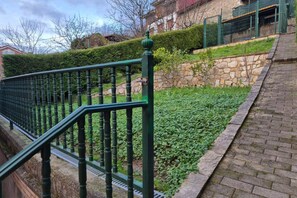Een groene metalen trap met een stenen muur en een haag op de achtergrond.