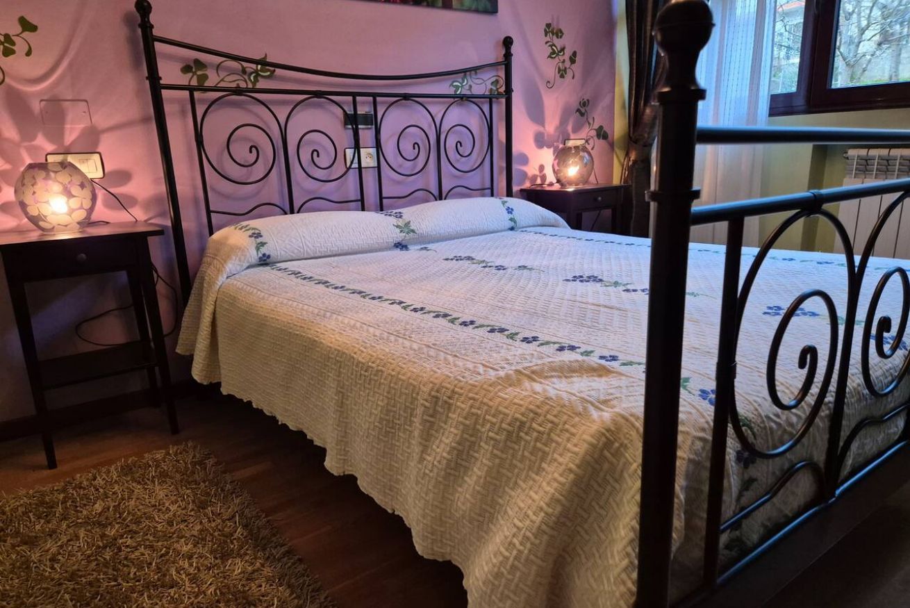 A bedroom with a metal bed frame, a bedside table with a lamp, and a rug on the floor.