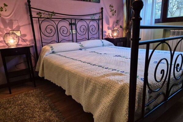 Une chambre à coucher avec un lit en métal, une table de chevet avec une lampe et un tapis sur le sol.