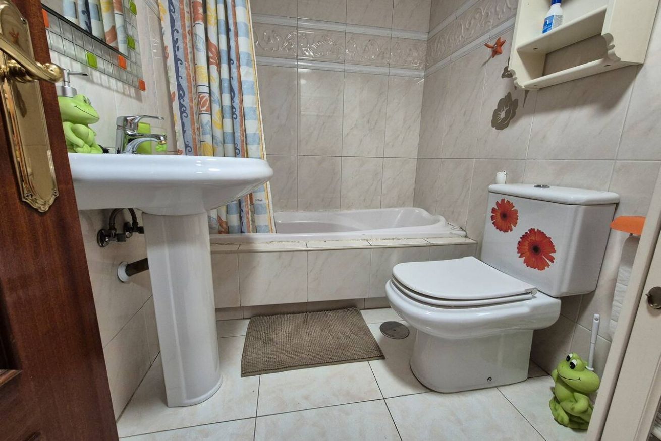 Un baño con lavamanos, inodoro, bañera y cortina de ducha.