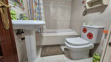 Un baño con lavamanos, inodoro, bañera y cortina de ducha.
