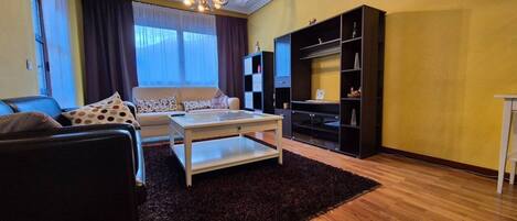 Una sala de estar con sofá, mesa de centro y mueble para la televisión.