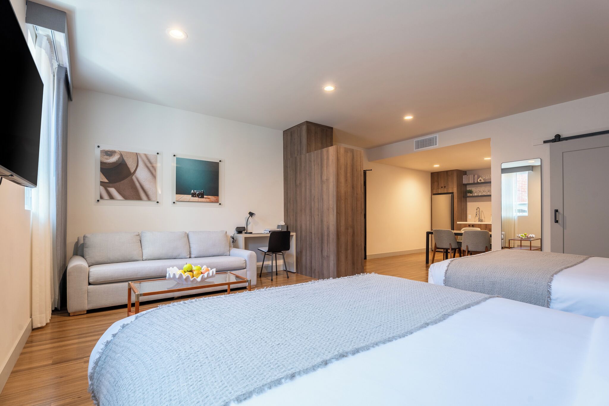 A hotel room with a bed, a sofa, a desk, and a kitchenette.