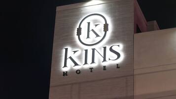 A hotel sign with the name 'KINS HOTEL' illuminated against a night sky.