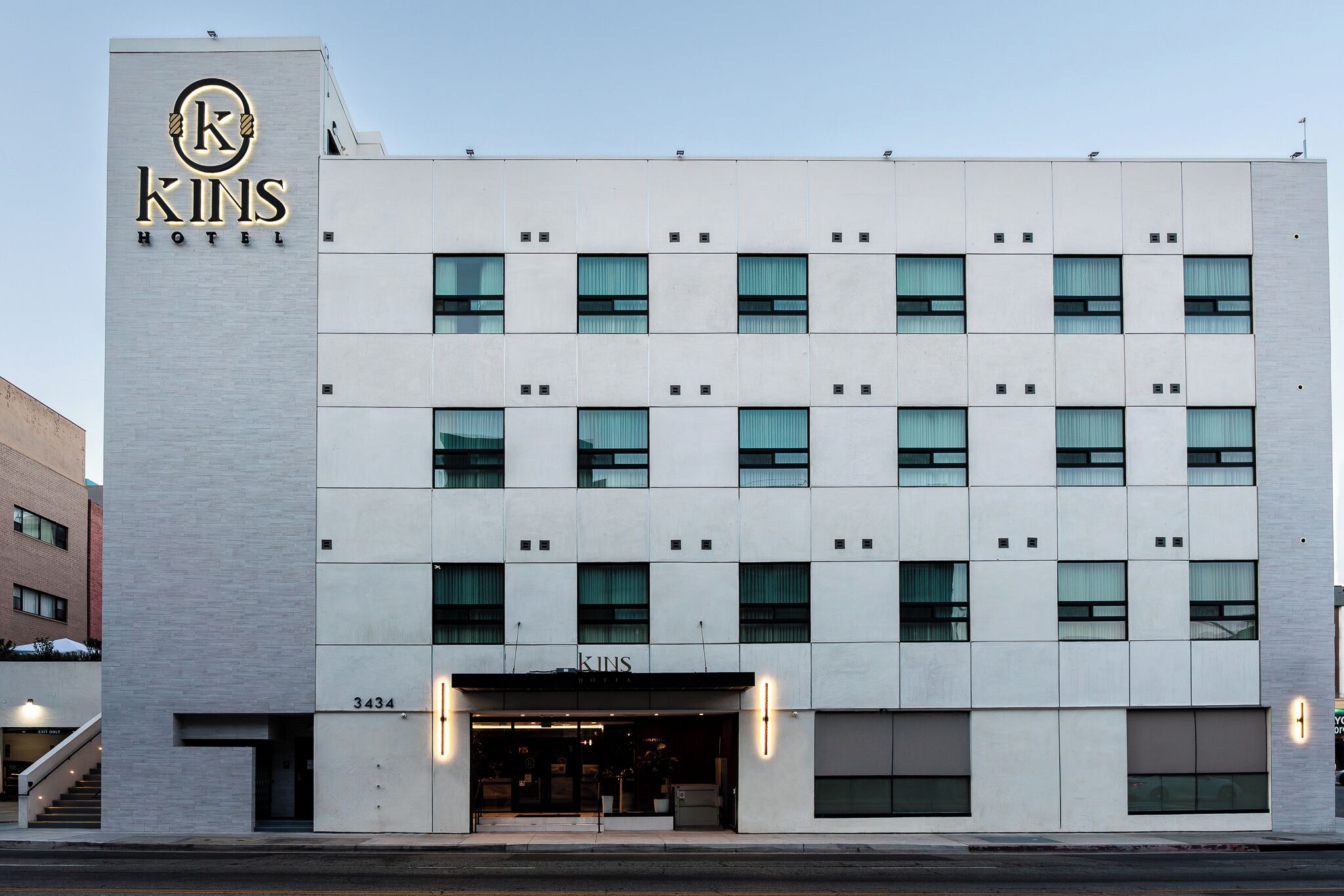Un hotel moderno con un logotipo destacado, varios pisos y una entrada visible.
