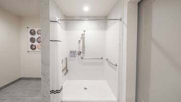 Un baño moderno con ducha a ras de suelo, barras de apoyo y suelo de baldosas.