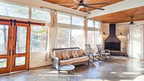 A spacious room with a wooden ceiling, large windows, a fireplace, and a sofa with chairs. - Lakefront Oasis | Hot Tub | Game Room | 3+ Acres (Stigler)