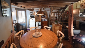 Una cocina rústica con vigas de madera, una mesa redonda de madera y una lámpara colgante.