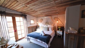 Un dormitorio con techo de madera, una cama con dosel, mesitas de noche y una mesilla.