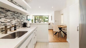 Une cuisine moderne dotée d’un grand îlot central, de meubles blancs et d’un dosseret carrelé.