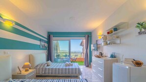 A bedroom with a bed, bedside table, lamp, and a view of the outdoors. - Blue Skyline | Sea View Terrace in Portisco (Olbia)