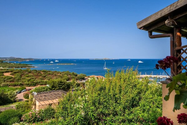 A coastal view with boats, greenery, and a building with a pergola.
