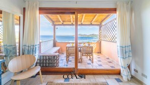 A balcony with a wooden table and chairs, a wooden bench, and a view of the sea. - Asfodeli - Flat with sea view and WiFi (Olbia)