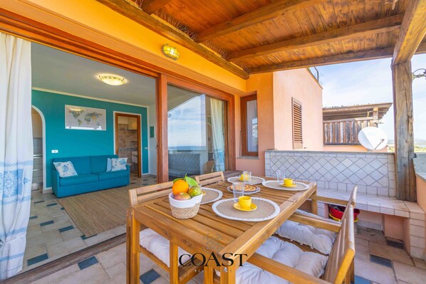 A dining area with a wooden table, chairs, and a buffet with fruits and drinks.