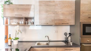 A modern kitchen with wooden cabinets, a stainless steel sink, and a built-in oven. - St. Simplicius - 5 mins from city center, WiFi, AC (Olbia)