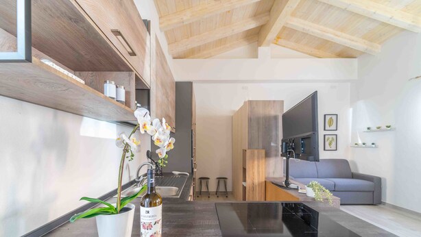 A modern kitchen with wooden cabinetry, a black countertop, and a potted orchid. - St. Simplicius - 5 mins from city center, WiFi, AC (Olbia)