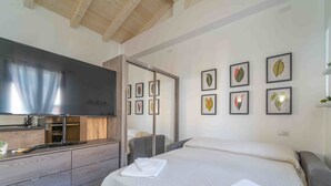 A modern bedroom with a bed, a TV, a wardrobe, and framed botanical prints on the wall. - St. Simplicius - 5 mins from city center, WiFi, AC (Olbia)