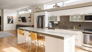 A modern kitchen with a central island, stainless steel appliances, and pendant lighting.