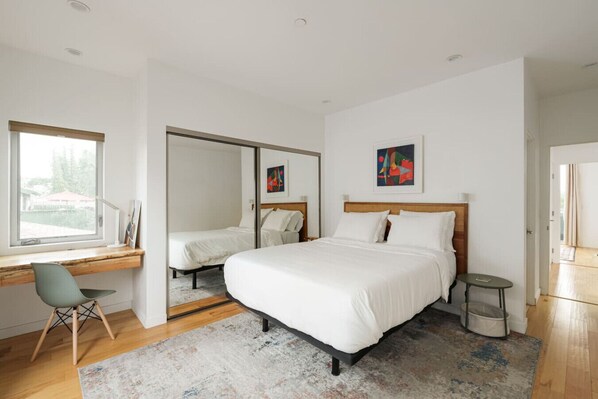 A modern bedroom with a large bed, a desk with a chair, and a small table.