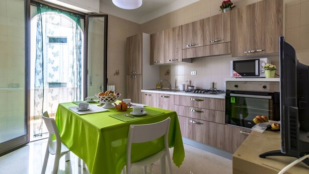 Eine moderne Küche mit Holzschränken, einer Mikrowelle, einem Backofen und einem Essbereich mit Tisch und Stühlen.