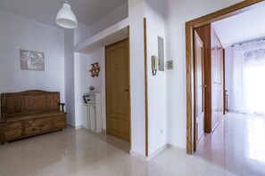 A hallway with a wooden bench, a door, and a small table with a plant.
