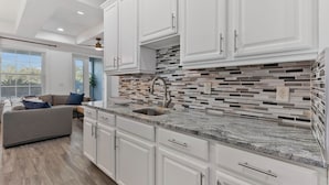 Eine moderne Küche mit weißen Schränken, einer Granitabdeckung und einer Mosaik-Spritzschutzwand.