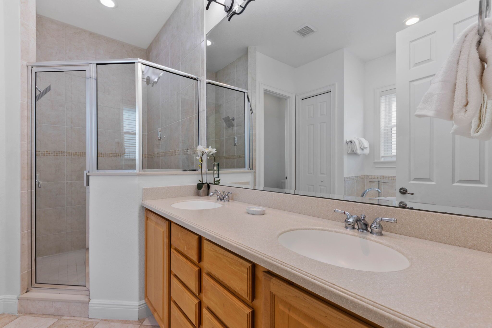 A modern bathroom with a glass shower enclosure, two sinks, and a large mirror.