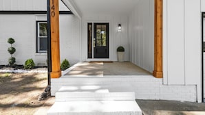 Un edificio bianco con una porta nera e un palo di legno con il numero 5140.