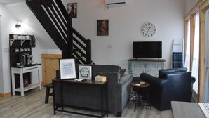 A living room with a staircase, a flat-screen TV, a sofa, a coffee table, and a small side table. - Family/Pet Friendly, Peaceful Cabin, Deck with seasonal Norfork Lake views

 
 (Henderson)
