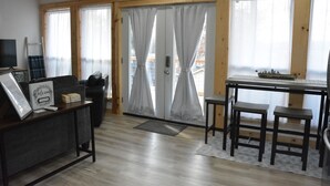 A room with a wooden-framed door, a small table with a chair, a TV on a stand, and a welcome sign. - Family/Pet Friendly, Peaceful Cabin, Deck with seasonal Norfork Lake views

 
 (Henderson)