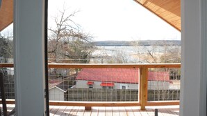 A wooden deck with a view of a red-roofed house and a bridge in the distance. - Family/Pet Friendly, Peaceful Cabin, Deck with seasonal Norfork Lake views

 
 (Henderson)
