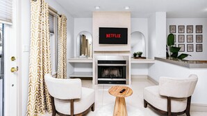 A modern living room with a fireplace, a mounted TV, and two armchairs.